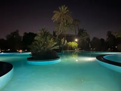 a large swimming pool at night with palm trees at Appartement au palmeraie Marrakech in Marrakech