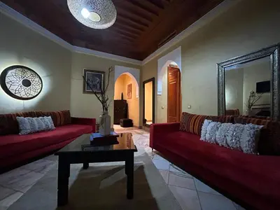 a living room with two red couches and a table at Appartement au palmeraie Marrakech in Marrakech