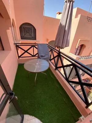 a table and a chair on a balcony with an umbrella at Séjour Étoilé in Marrakech