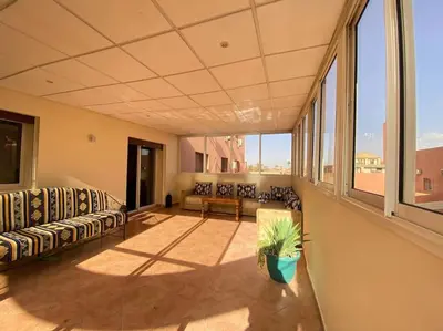 a large room with couches and a table and windows at Superbe Appartement avec Véranda et Terrasse in Marrakech