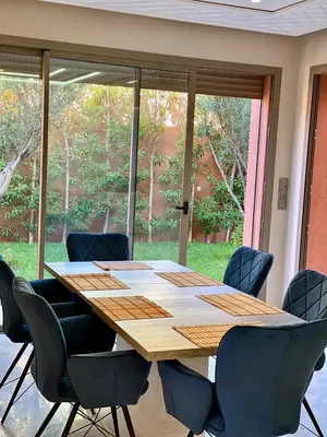 a large wooden table with chairs and a large window at villa de luxe avec piscine privée in Marrakech