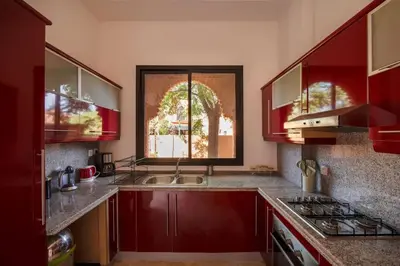a kitchen with red cabinets and a sink and a window at Villa Leya - Piscine chauffée in Marrakech