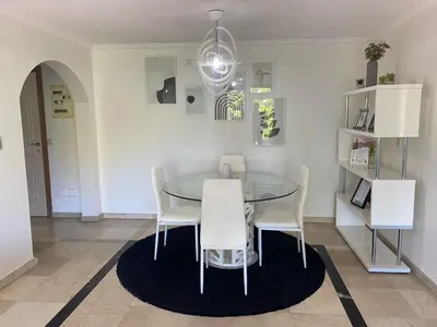 a dining room with a glass table and white chairs at Appartement cosy à deux pas du Jardin Majorelle in Marrakech