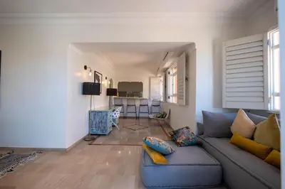 a living room with a blue couch and a kitchen at Élégant appartement avec terrasse au cœur Guéliz in Marrakech