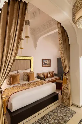 a bedroom with a king sized bed and curtains at Riad Laz Mouassine & Wellness in Marrakech