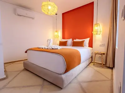 a bedroom with a large bed with an orange wall at Riad Abati Piscine Privee avec Petit dejeuner et Terrasse in Marrakech