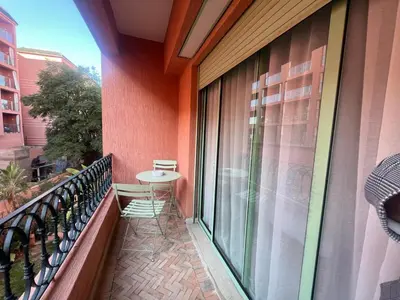 a balcony with a table and a glass window at Bel Appartement meublé avec Piscine, l'hivernage à Marrakech in Marrakech