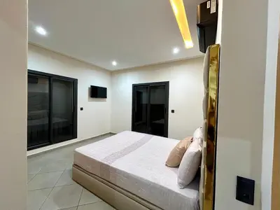 a bedroom with a bed and two large windows at Appartement a Gueliz in Marrakech