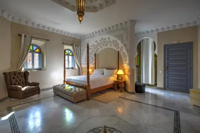 a bedroom with a bed and a chair and a mirror at Ksar Anika Boutique Hotel & Spa in Marrakech