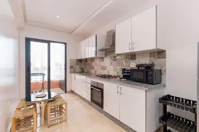 a kitchen with white cabinets and a table and a microwave at Luxury and Healthy designed Apartment with pool in Marrakech