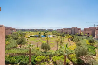 a park in a city with palm trees and buildings at Cute And Modern Appart In Prestigia in Marrakech