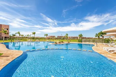 a large swimming pool with blue water and palm trees at 2Bedrooms In Prestigia - Very Well Equipped With View in Marrakech