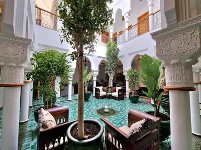 a hotel lobby with a tree in a fountain at Riad LakLak Nouvelle 400m2 mit Pool in der Medina in Marrakech
