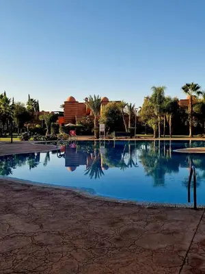 a large pool of water with palm trees and buildings at Dar Ou Bahssou in Marrakech