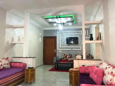 a living room with purple couches and a tv at AC Family apartment steps away from everything in Marrakech