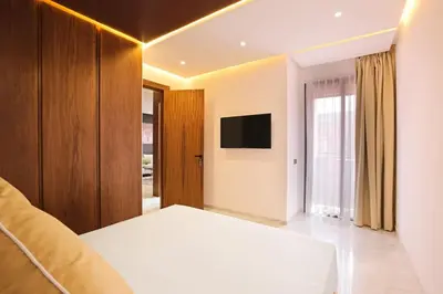 a bedroom with a white bed and a television at Brand New and Stylish appart hotel Best location in Marrakech