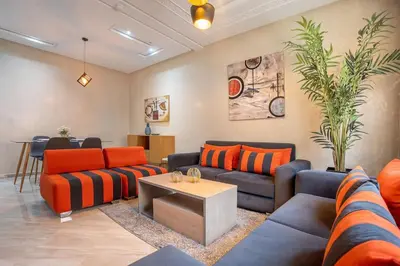 a living room with orange and blue couches and a table at Charming two bedrooms Flat with Pool and Parking in Marrakech
