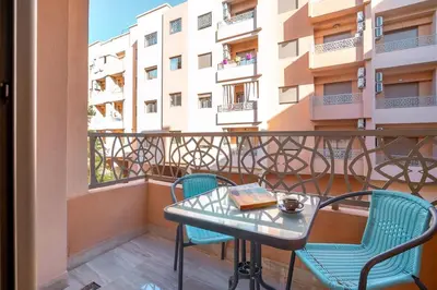 a table and chairs on a balcony with a building at Spacious 2 BR FLAT with Wi-Fi, Pool and Parking in Marrakech