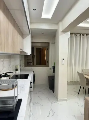 a kitchen with white marble counter tops and a table at Appartement Cosy in Marrakech