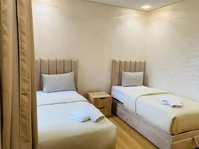 two beds in a small room with white sheets at Expérience luxueuse Golf Prestigia Saphir BY KECH in Marrakech