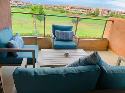 a balcony with two blue chairs and a coffee table at Expérience luxueuse Golf Prestigia Saphir BY KECH in Marrakech