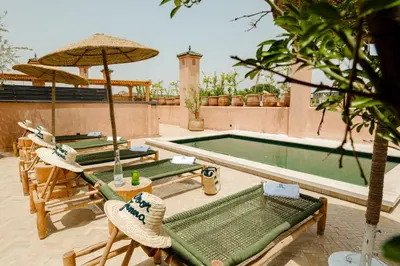 a pool with chairs and umbrellas next to at Door Janna in Marrakech