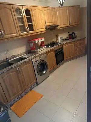 a kitchen with wooden cabinets and a washing machine at Magnifique appartement 2 chambres et piscine de standing in Marrakech