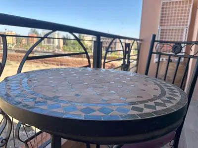 a stone table on a balcony with a table at Magnifique appartement 2 chambres et piscine de standing in Marrakech