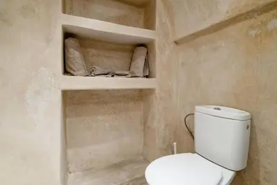 a bathroom with a toilet and towels on shelves at Riad LakLak Tradition 350m2 in der Medina mit Terrasse in Marrakech