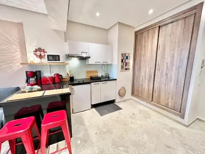 a kitchen with white cabinets and red stools at Appartement elegant et securise au centre de Marrakech in Marrakech