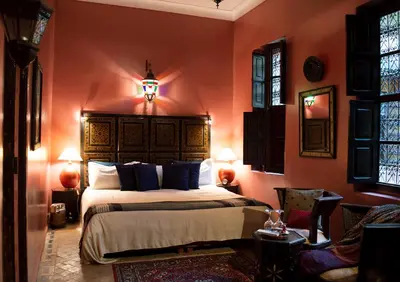 a bedroom with a large bed with orange walls at Riad Amirat Al Jamal in Marrakech