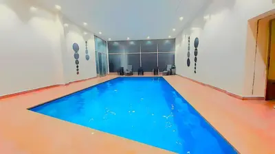 an indoor swimming pool with blue water in a building at Le Spacieux de Gueliz avec Piscine et Terasse in Marrakech