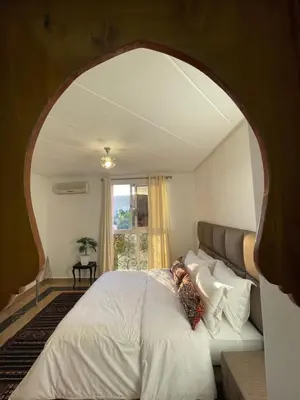 a bedroom with a large white bed with an archway at Refined apartment DOWNTOWN in Marrakech