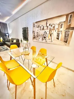 a living room with a table and yellow chairs at Appartement Sofia in Marrakech