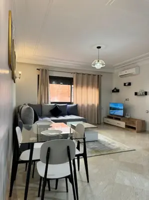 a living room with a couch and a table and chairs at Cosy Appartement Famille in Marrakech