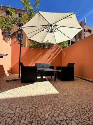 a table and chairs and an umbrella on a patio at Cosy Appartement Famille in Marrakech