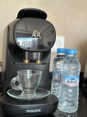 a coffee maker with a cup and two bottles of water at Luxueux appartement Golf Noria in El Makina