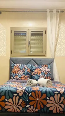 a bedroom with a bed with a floral bedspread at Cozy Apartment Near Airport Terminal Modern Apartment Close to Airport in Marrakech
