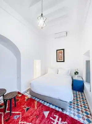 a bedroom with a white bed and a red rug at Riad Dar Cidi 100m2 in der Medina mit Terrasse in Marrakech