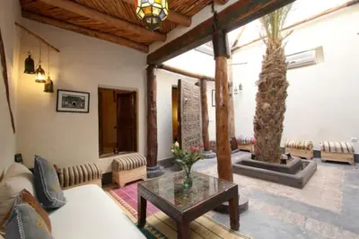a living room with a palm tree and a table at Riad Petit Palais 100m2 in der Medina mit Terrasse in Marrakech