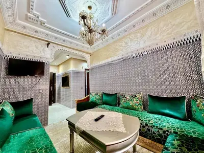 a living room with a green couch and a chandelier at appart Confortable BASSATIN GUILIZ in Marrakech