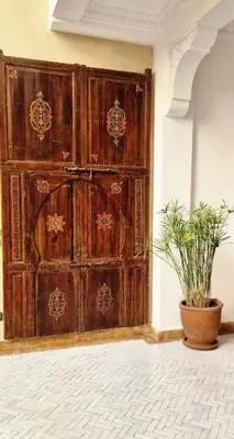 a large wooden door in a room with a potted plant at Riad Babmoon - Private Riad with Pool & Rooftop in Marrakech