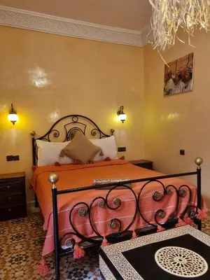 a bedroom with a bed with an orange bedspread at Riad Benrahal in Marrakech
