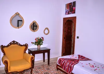 a bedroom with a bed and a chair and a table at Riad Benrahal in Marrakech