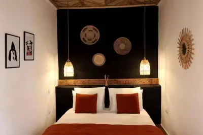a bedroom with a bed with a black headboard and orange pillows at Riad Ptit Kech, Bassin terrasse - Petits déjeuners in Marrakech