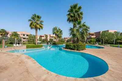 a swimming pool in a resort with palm trees at stylish appart with 3Bedrooms in Prestigia in Marrakech