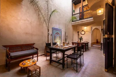 a dining room with a table and chairs and a staircase at Riad Dar Haris in Marrakech