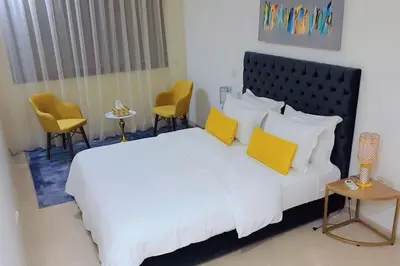 a bedroom with a bed with yellow pillows and chairs at Appartement familial de luxe in Marrakech
