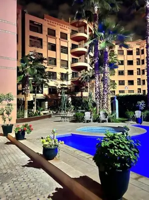 a building with a swimming pool and some plants at Appartement Marrakech Hivernage N4 RESIDENCE CAPRICE PALACE in Marrakech