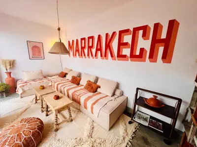 a living room with a couch and a sign on the wall at Votre riad privé en médina avec services inclus in Marrakech